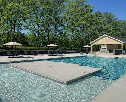A swimming pool with a diving board and lounge chairs.