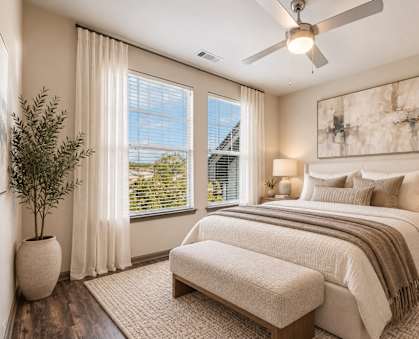 A bedroom with a large bed, a bench, and a ceiling fan.