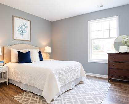 A bedroom with a white bed and a white nightstand with a lamp.