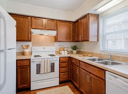 A kitchen with wooden cabinets and a white stove top oven.