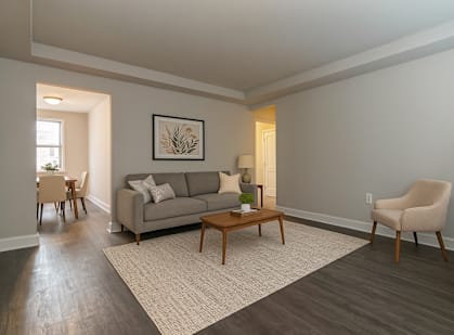 A living room with a grey couch, a wooden coffee table, a beige armchair, and a framed picture on the wall.