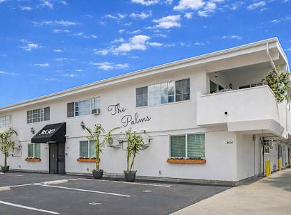 The Palms building has a black awning and a yellow door.
