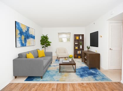A living room with a grey couch and a blue and yellow painting on the wall.