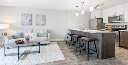 A modern kitchen with a white sofa and grey bar stools.