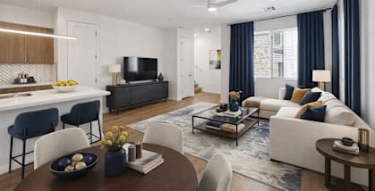 A modern living room with a white sofa, a wooden coffee table, and a dark-colored television.