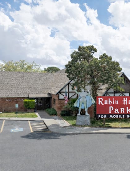 A sign for Robin Hood Park for mobile homes stands in front of a building.
