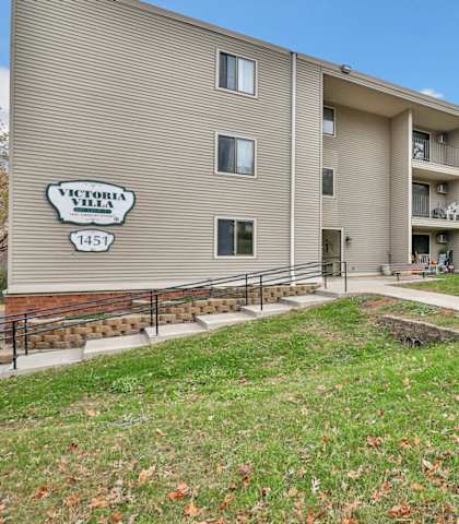 a large apartment building with stairs and a green lawn
