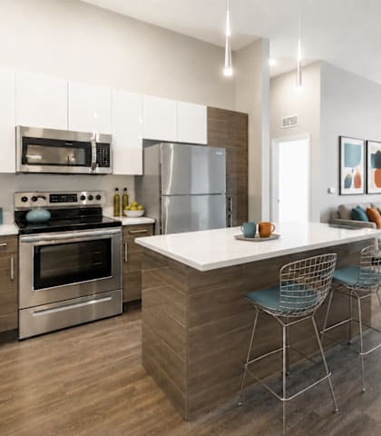 A modern kitchen with a large island and a view of the outdoors.