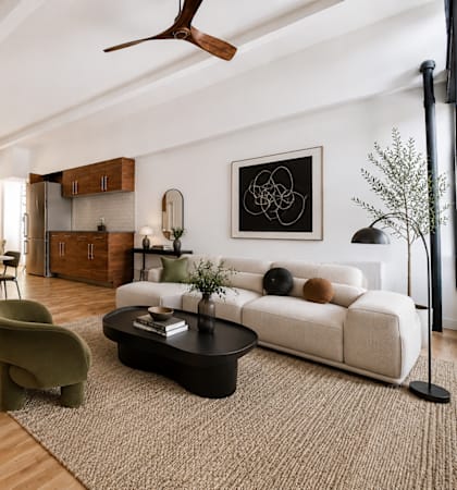 A modern living room with a white sofa, wooden floors, and a large rug.