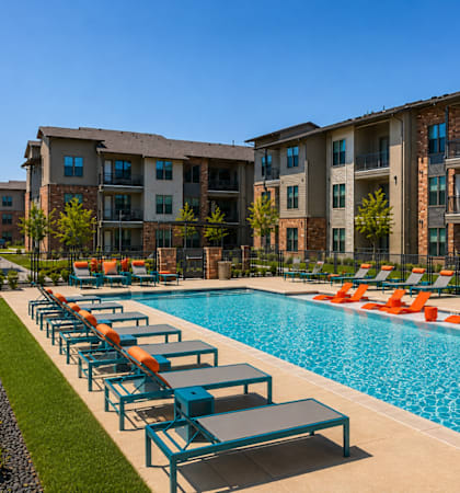 Resort-style swimming pool with in-water loungers and spacious sundeck at One Preston Station Apartments.
