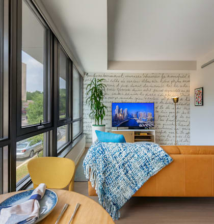 A bedroom with a bed, a chair, and a table with a plate on it.