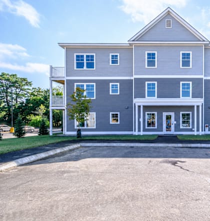 Three story residential building with gray siding at Windham Village Apartments, Windham, Maine