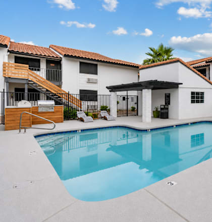A swimming pool in front of a white building with a black fence.