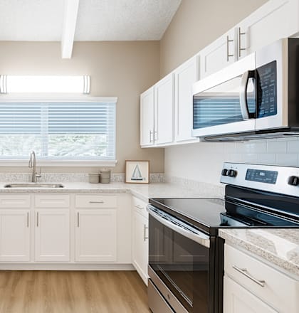 A kitchen with white cabinets and black appliances.