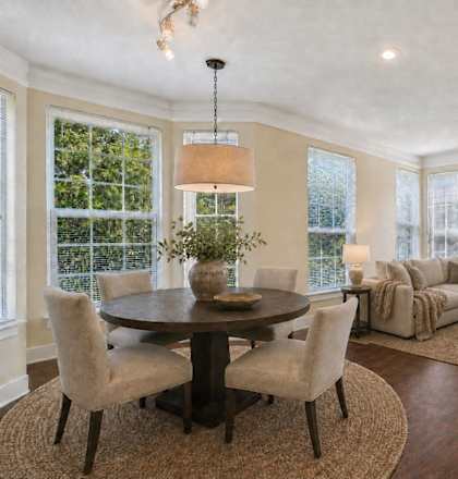 A well-lit living room with a round table and chairs.