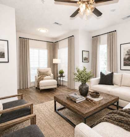 A living room with a white couch, a wooden coffee table, and a ceiling fan.
