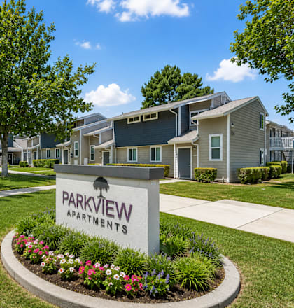 A sign that says Parkview Apartments is in front of some houses.