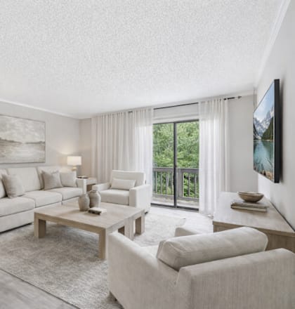 A well-lit, spacious living room with a large window and a view of the outdoors.