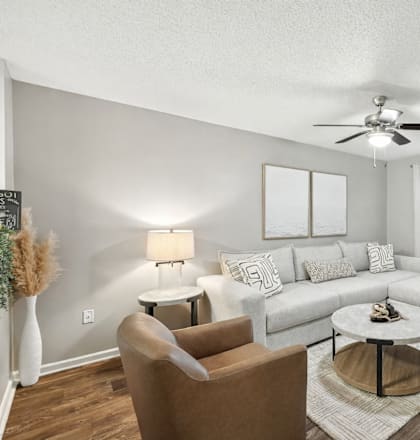 A living room with a brown chair, a white couch, and a ceiling fan.