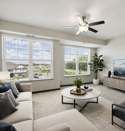 A living room with a large couch, a coffee table, and a flat-screen TV.