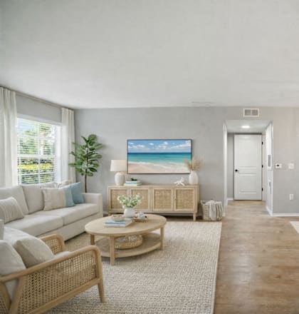 A living room with a white couch, a coffee table, and a painting on the wall. at Waterbridge Apartments , Orlando, FL, 32837