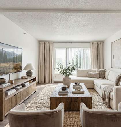 A living room with a white couch, a wooden coffee table, and a flat-screen TV.