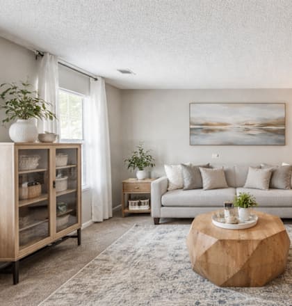 A living room with a couch, a coffee table, and a painting on the wall.