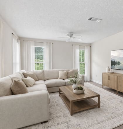 A living room with a large couch, a coffee table, and a painting on the wall.