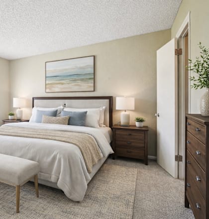 A bedroom with a large bed, a bench, and a painting on the wall.