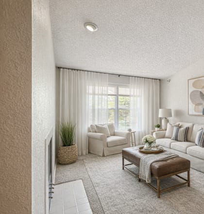 A living room with a white couch, a coffee table, and a painting on the wall.