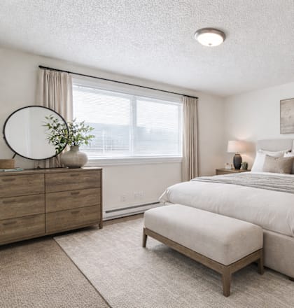 A bedroom with a large bed, a dresser, and a nightstand.