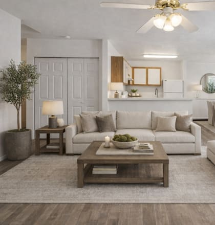 A modern living room with a white sofa set, a wooden coffee table, and a large mirror on the wall.