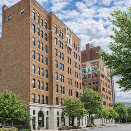A large red brick building with many windows and trees in front.