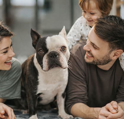 A family of three is sitting together with a dog.