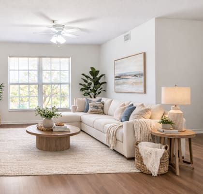 A living room with a white couch, wooden coffee table, and a large window.