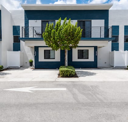 A white and blue building with a tree in front.