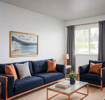 A living room with a blue sofa, a painting on the wall, and a glass table with a vase on it.