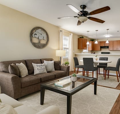 A living room with a brown couch and a glass coffee table.