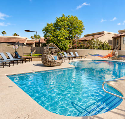 A swimming pool with a metal ladder and a few chairs.