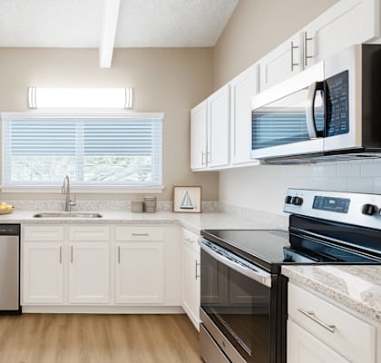 A kitchen with white cabinets and black appliances.