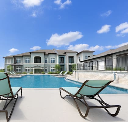 A pool with chairs and a building in the background.