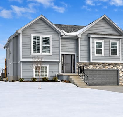 A house with a grey exterior and a black garage door.