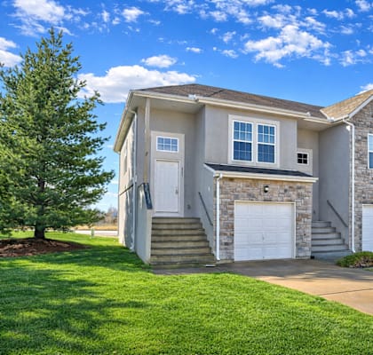 A large house with a garage is surrounded by a green lawn.