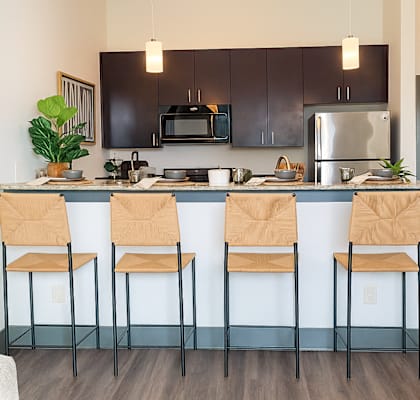 A kitchen with black cabinets and a blue island.