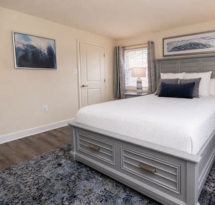 A bedroom with a large bed and a painting on the wall.