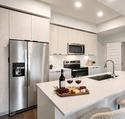A modern kitchen with a white countertop and stainless steel appliances.