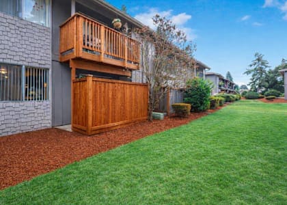 A house with a wooden deck and a red mulch garden bed.
