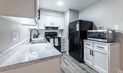 A kitchen with a black refrigerator and white cabinets.