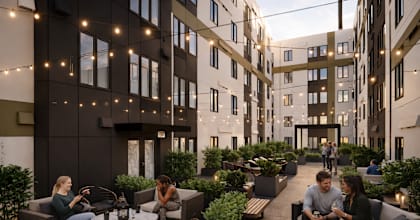 People are sitting and talking in a courtyard surrounded by buildings.