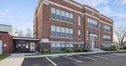 A large red brick building with a parking lot in front.
